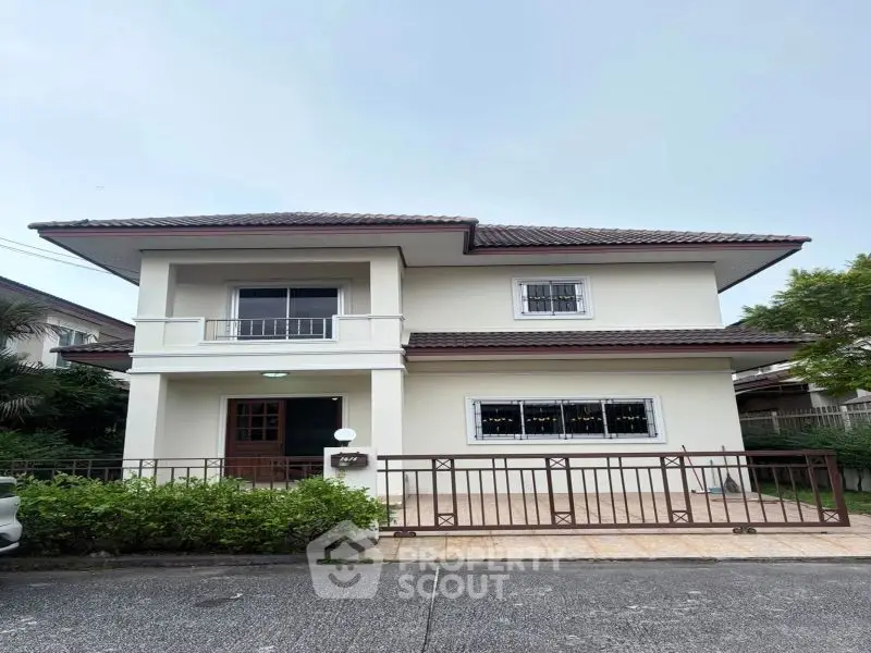 Charming two-story house with a tiled roof and fenced front yard in a serene neighborhood.