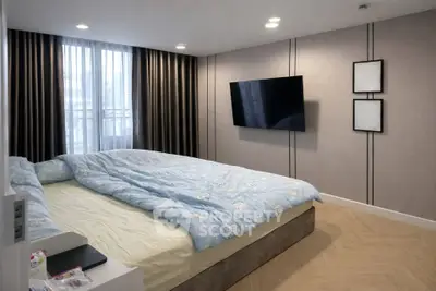 Modern bedroom with stylish decor and wall-mounted TV, featuring large windows and elegant curtains.