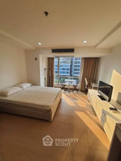 Spacious bedroom with large window and natural light in modern apartment