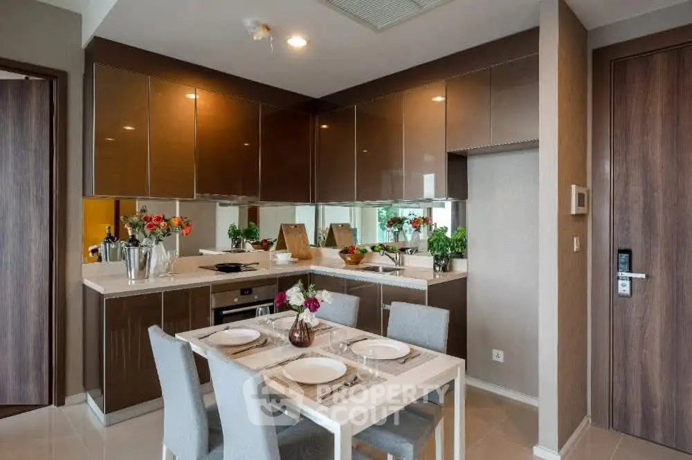 Modern kitchen with sleek cabinetry and dining area, featuring elegant decor and ample lighting.