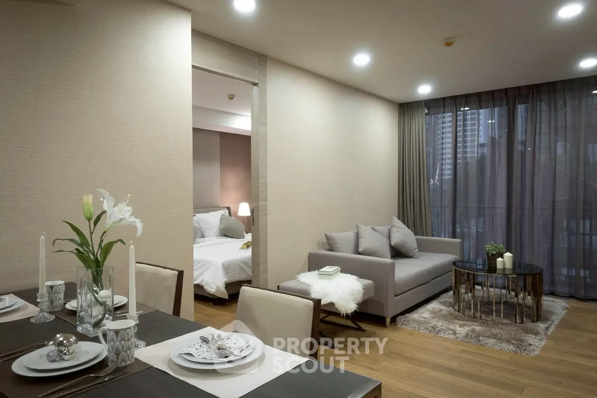 Modern open-plan living room with elegant dining area and cozy bedroom view.