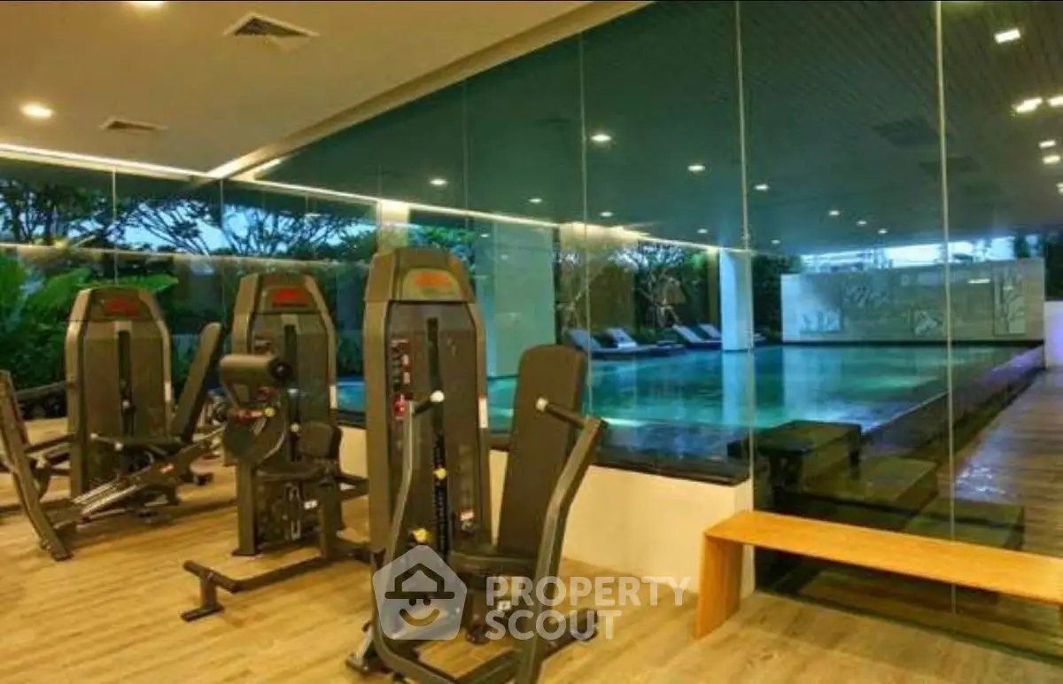 Luxurious indoor gym with pool view in modern residential complex