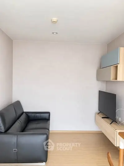 Modern living room with sleek black sofa and mounted TV in minimalist design.