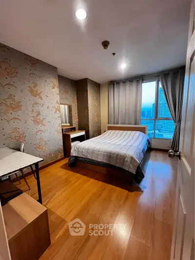 Cozy bedroom with city view, wooden flooring, and modern decor in a high-rise apartment.