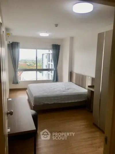 Spacious bedroom with large window offering scenic view, modern furnishings, and ample natural light.