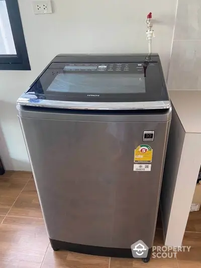 Modern washing machine in a sleek laundry area with wooden flooring.