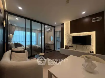 Modern open-plan living room with stylish decor and glass partition to bedroom