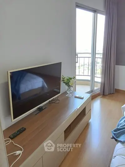 Modern living room with TV and balcony access, featuring sleek wooden flooring and elegant decor.