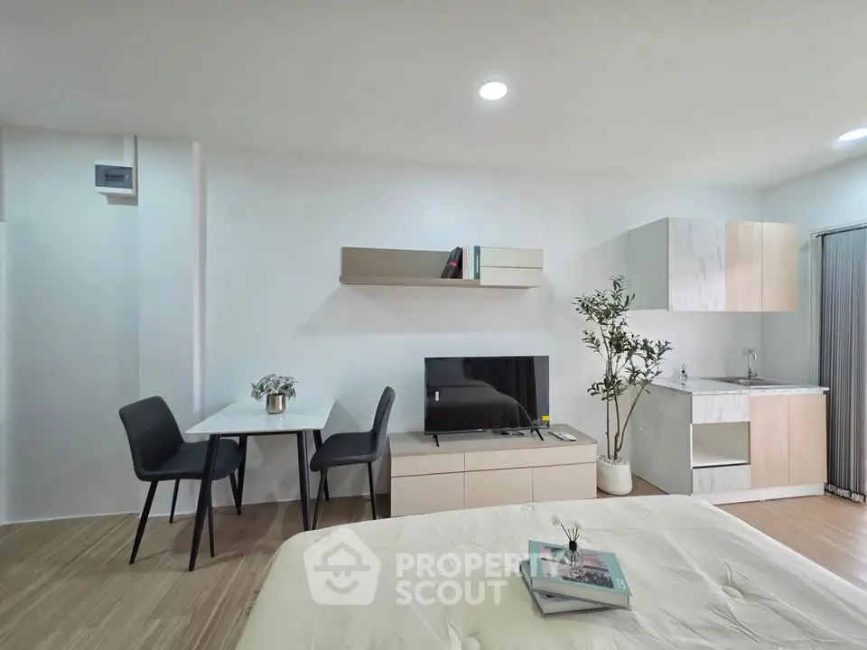 Modern studio apartment with sleek furniture and compact kitchen area, perfect for urban living.