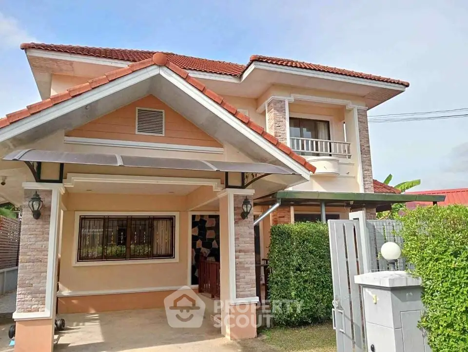 Charming two-story house with red roof and lush greenery, perfect for family living.