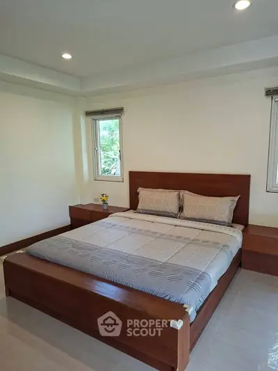 Spacious bedroom with modern wooden bed and natural light from windows