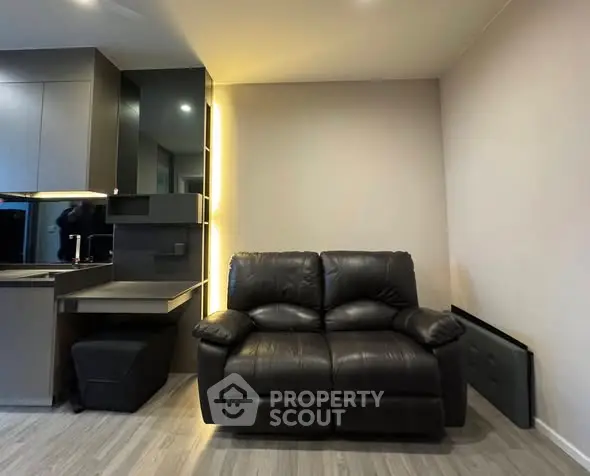 Modern living room with sleek leather sofa and stylish kitchen area, perfect for urban living.