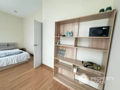 Spacious bedroom with wooden flooring and modern shelving unit