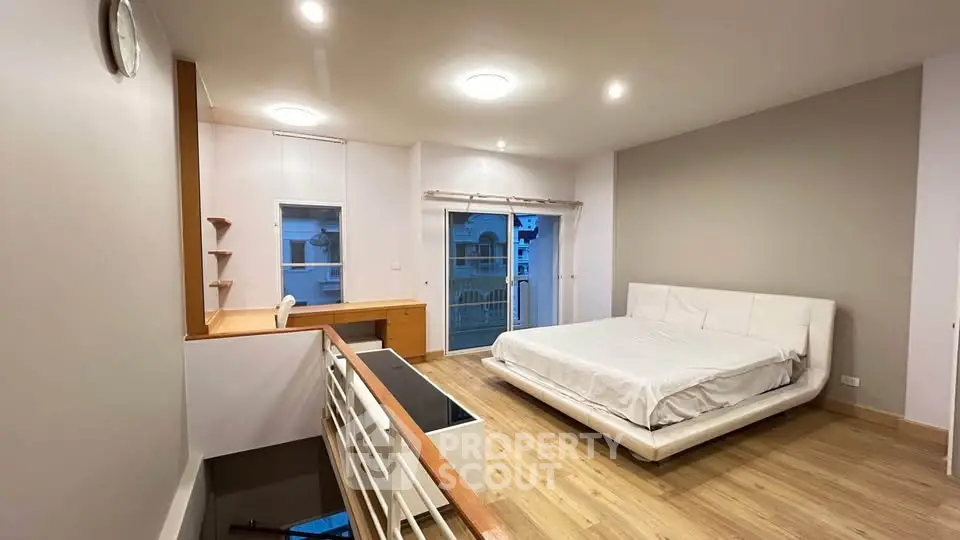 Spacious modern bedroom with wooden flooring and stylish furniture in a bright apartment.