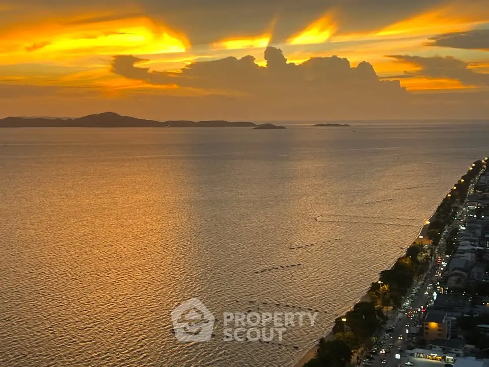 Stunning sunset view over the ocean with vibrant sky and coastal cityscape, perfect for beachfront living.