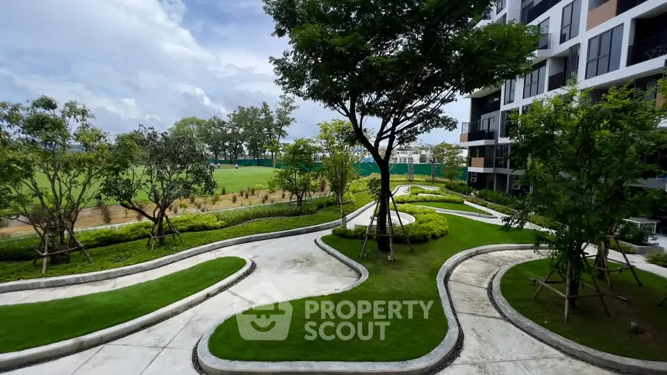 Modern apartment building with lush landscaped garden and winding pathways.