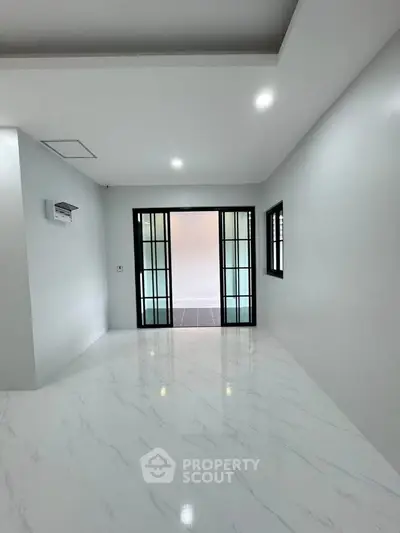 Spacious modern interior with sleek marble flooring and sliding glass doors, perfect for contemporary living.