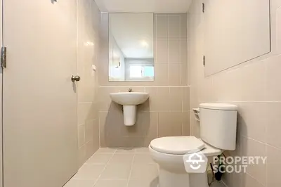 Modern bathroom with sleek fixtures and neutral tiles, featuring a wall-mounted sink and toilet.