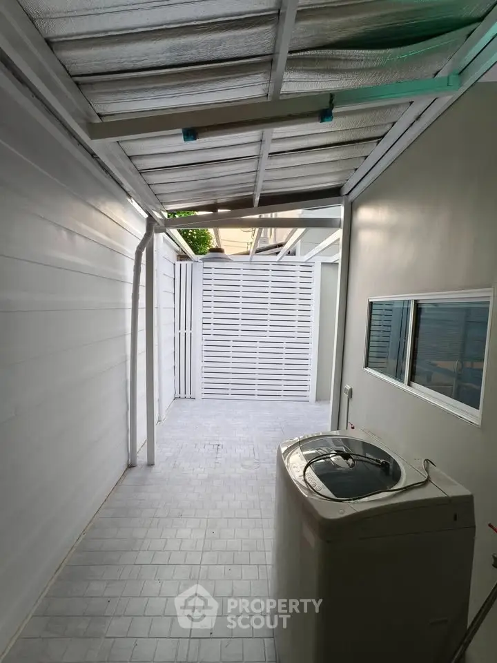 Covered outdoor laundry area with washing machine and tiled flooring