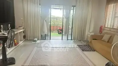 Spacious living room with large windows and garden view, perfect for relaxation and family gatherings.