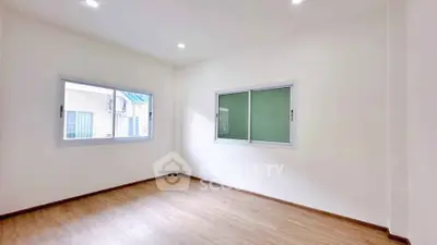 Spacious empty room with large windows and wooden flooring, ideal for customization.