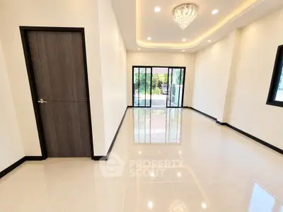 Spacious modern living room with elegant chandelier and large windows for natural light.