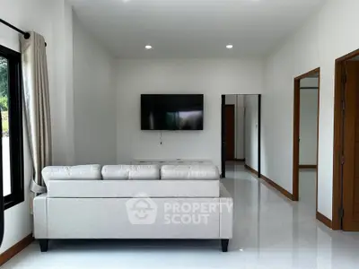 Modern living room with sleek design and wall-mounted TV, perfect for relaxation.