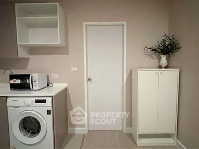 Modern laundry room with washing machine and microwave in sleek cabinetry.