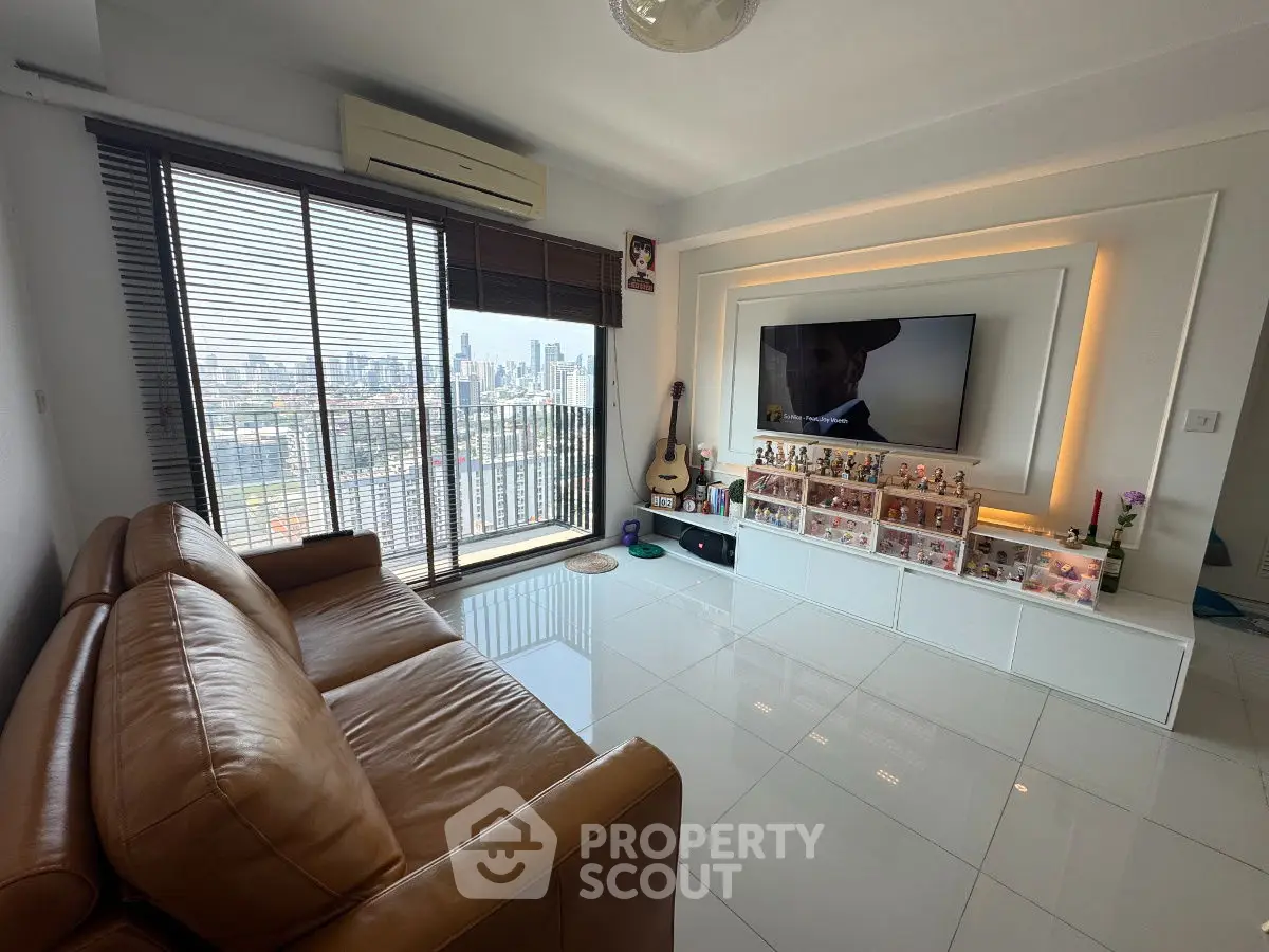 Modern living room with city view, leather sofa, and entertainment center.