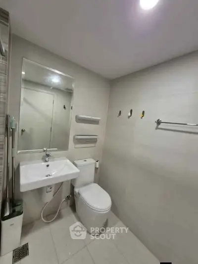 Modern bathroom with sleek fixtures and minimalist design, featuring a wall-mounted sink and toilet.