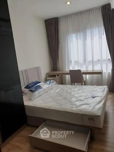 Cozy bedroom with natural light, featuring a bed, desk, and modern decor.