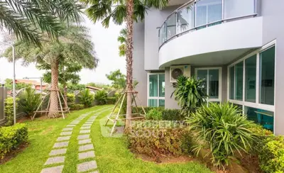 Modern building exterior with lush garden and curved balcony design.