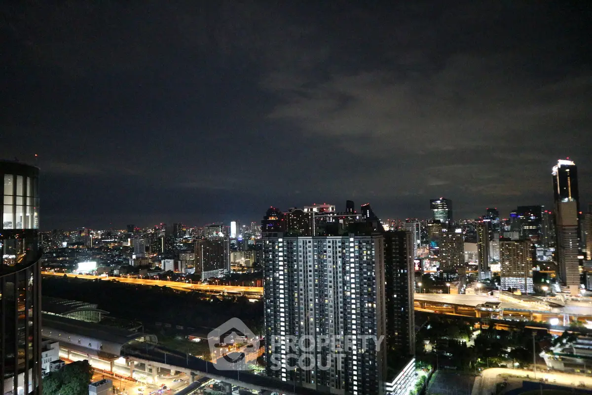 Stunning cityscape view from high-rise apartment at night, showcasing vibrant urban skyline and illuminated buildings.
