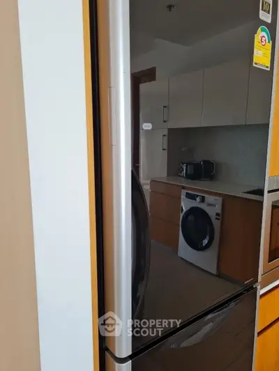 Modern kitchen with sleek appliances including fridge and washing machine, perfect for contemporary living.