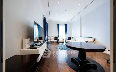 Elegant living room with hardwood floors, large TV, and stylish furniture in a modern apartment.