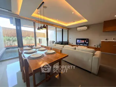 Luxurious open-plan living room with modern dining area and pool view, perfect for entertaining.