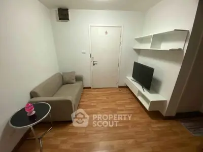 Cozy living room with modern sofa, TV, and wooden flooring in a compact apartment.