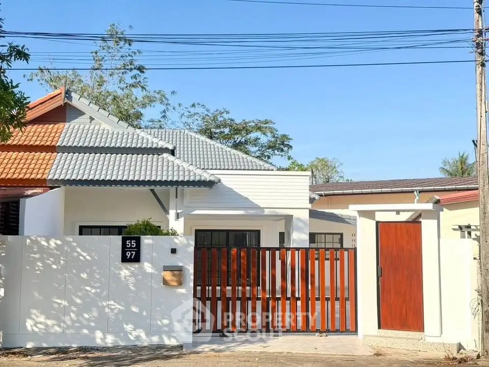 Charming single-story home with modern wooden gate and white fence in a serene neighborhood.