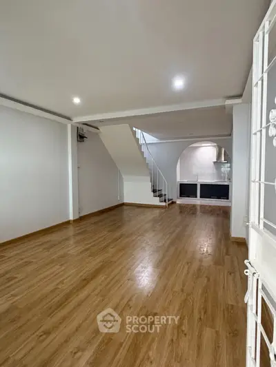 Spacious open-plan living area with wooden flooring and modern staircase, perfect for contemporary living.