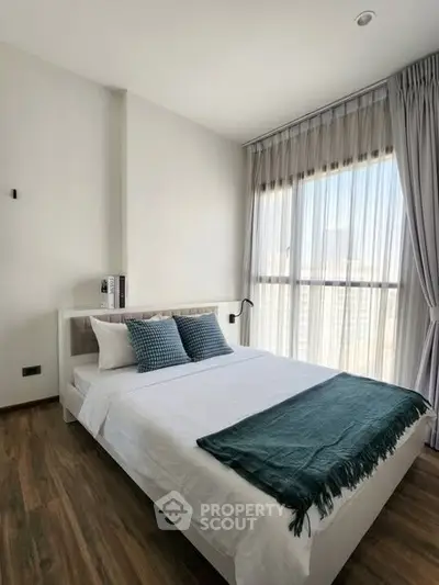 Modern bedroom with large window and stylish decor in a bright apartment.