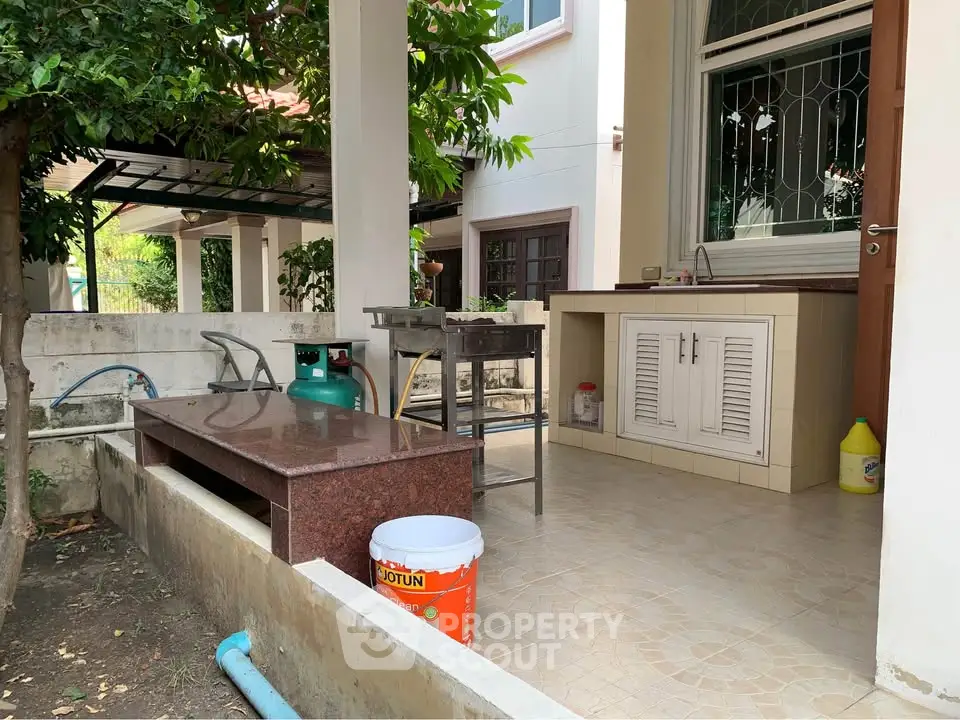 Charming outdoor kitchen area with tiled flooring and garden view, perfect for al fresco dining.
