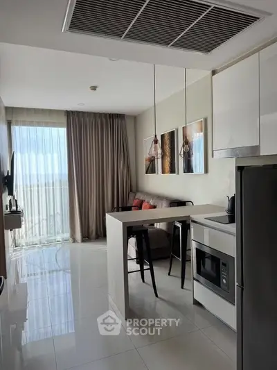 Modern open-layout kitchen and living room with stylish decor and natural light.