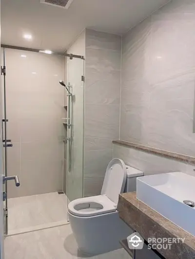 Sleek modern bathroom with glass shower enclosure, elegant tiling, and contemporary fixtures, perfect for a refreshing and stylish start to the day.