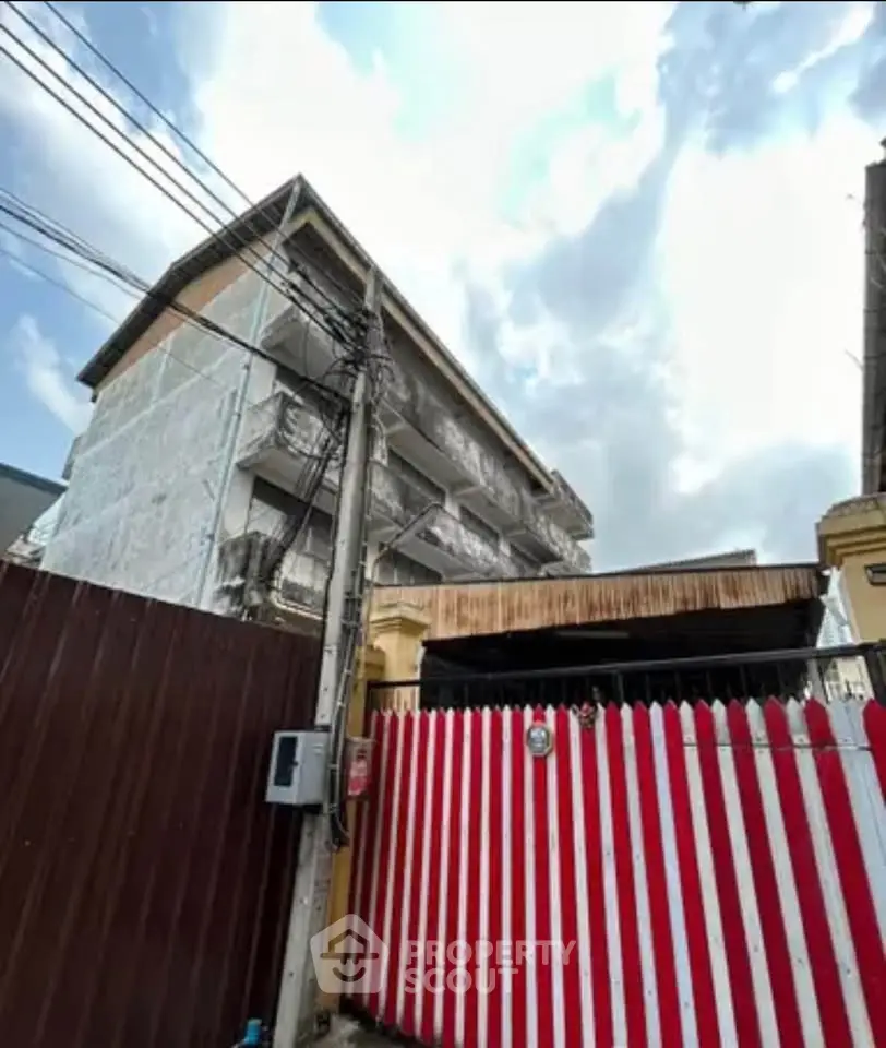 Explore this unique building exterior with striking red and white fence, perfect for investment opportunities.