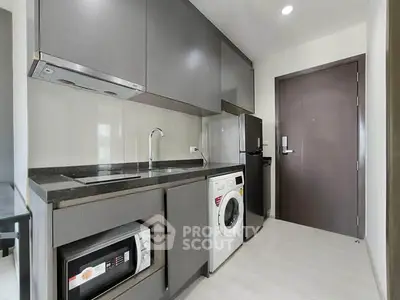 Modern kitchen with sleek cabinets, washing machine, and compact appliances in a stylish apartment.