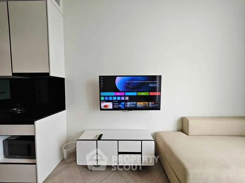 Modern living room with sleek furniture and wall-mounted TV in a stylish apartment.