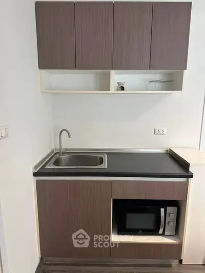 Modern compact kitchen with sleek cabinetry and built-in microwave