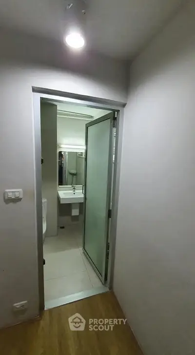 Modern bathroom entrance with frosted glass door and sleek fixtures