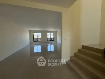 Spacious open-plan living area with glossy tiled floors and large windows.