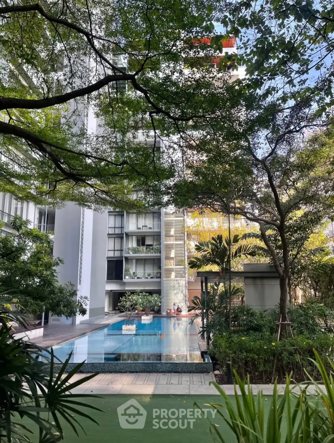 Luxurious residential building with serene pool and lush greenery, perfect for urban living.